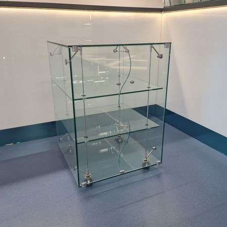 Eine kleine Kommode aus Glas mit geschwungenen Türen